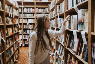 A girl searching books in a library.