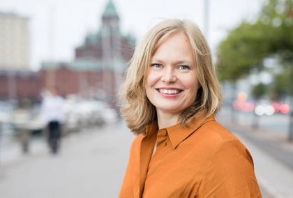 Minister of Science and Culture Hanna Kosonen in a orange dress photographed on a street in Helsinki