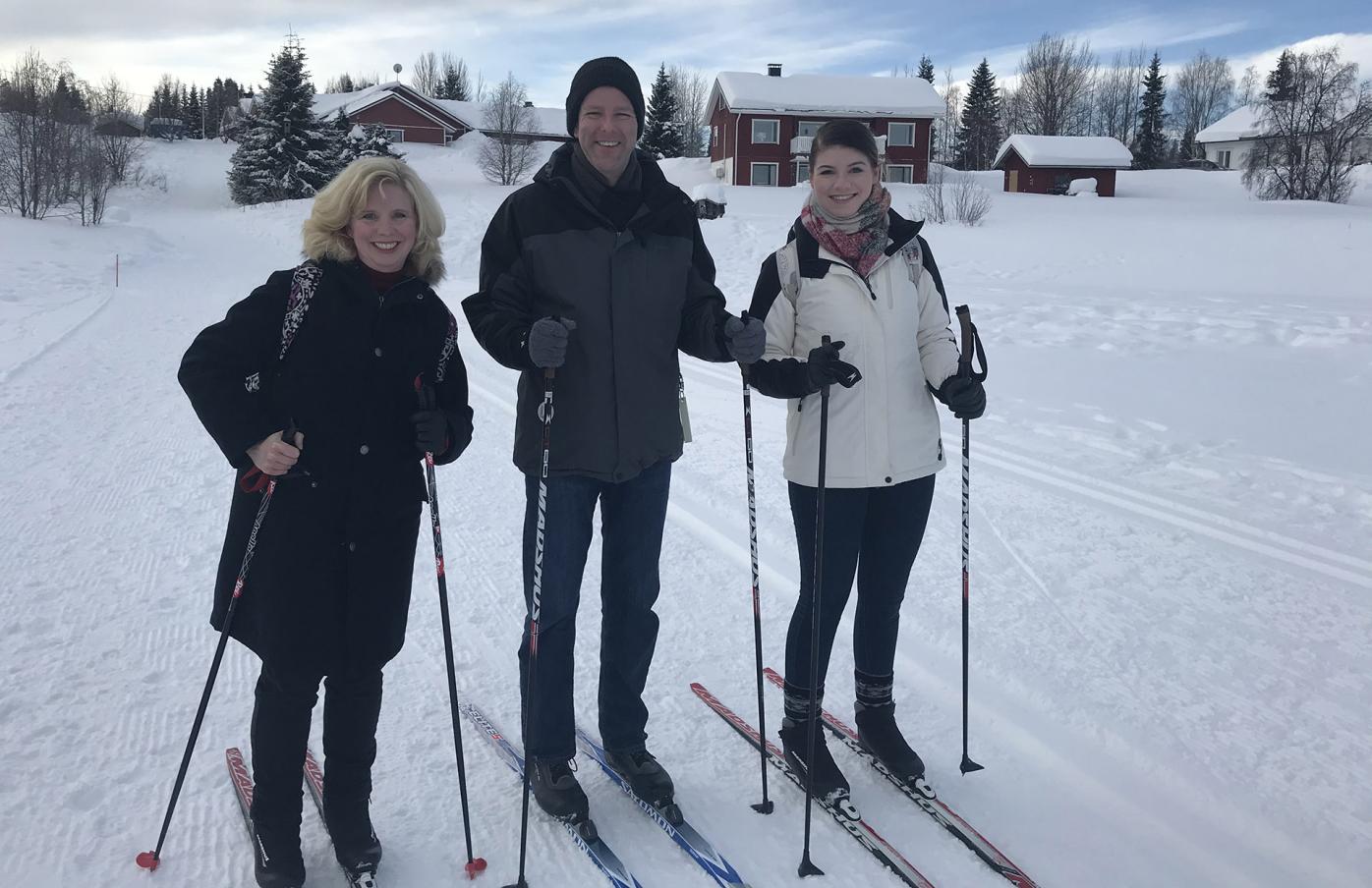 The Buchanan family on cross-country skiis at Ylläs, there is snow around them, and they are all smiling at the camera.