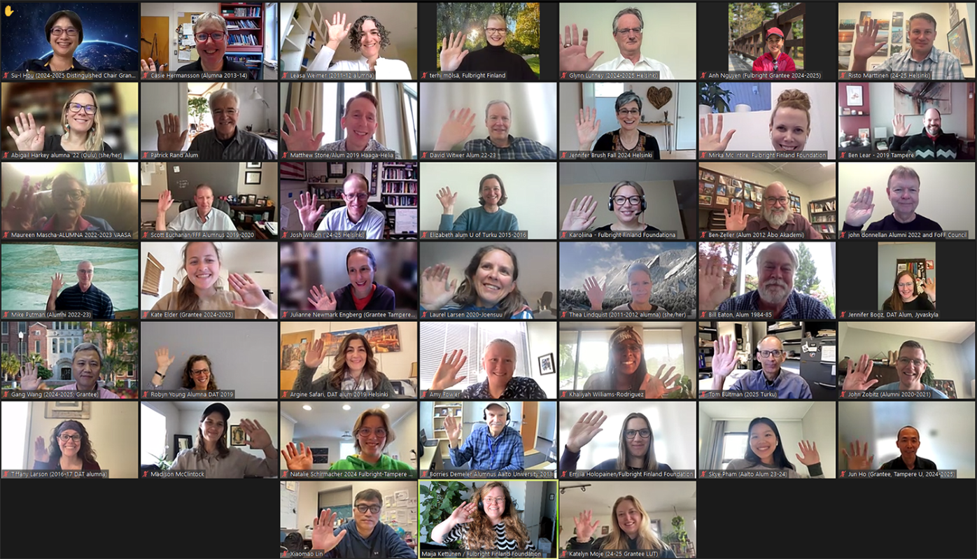 Screen capture of a Zoom call with many people waving and smiling at the camera