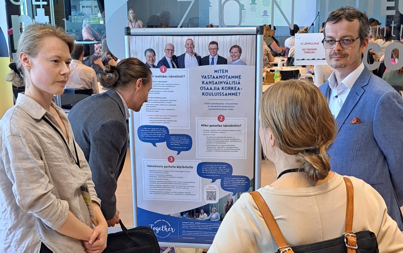 People gathered around a poster by Fulbright Finland Foundation at the Spring Forum 2024 at SeAMK campus.
