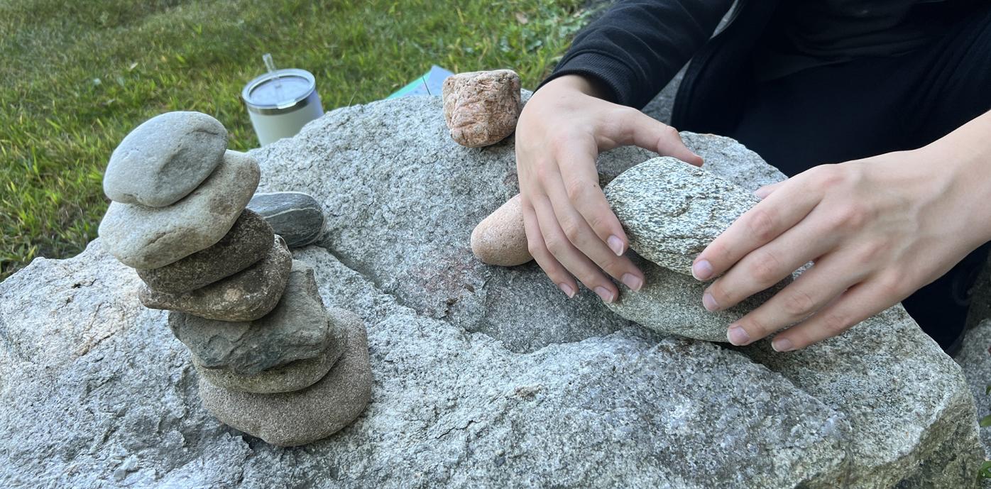 A person is balancing stones on top of each other, only hands of the person are showing.