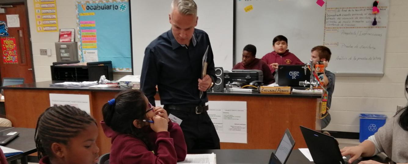 Teacher observing students' work in a classroom