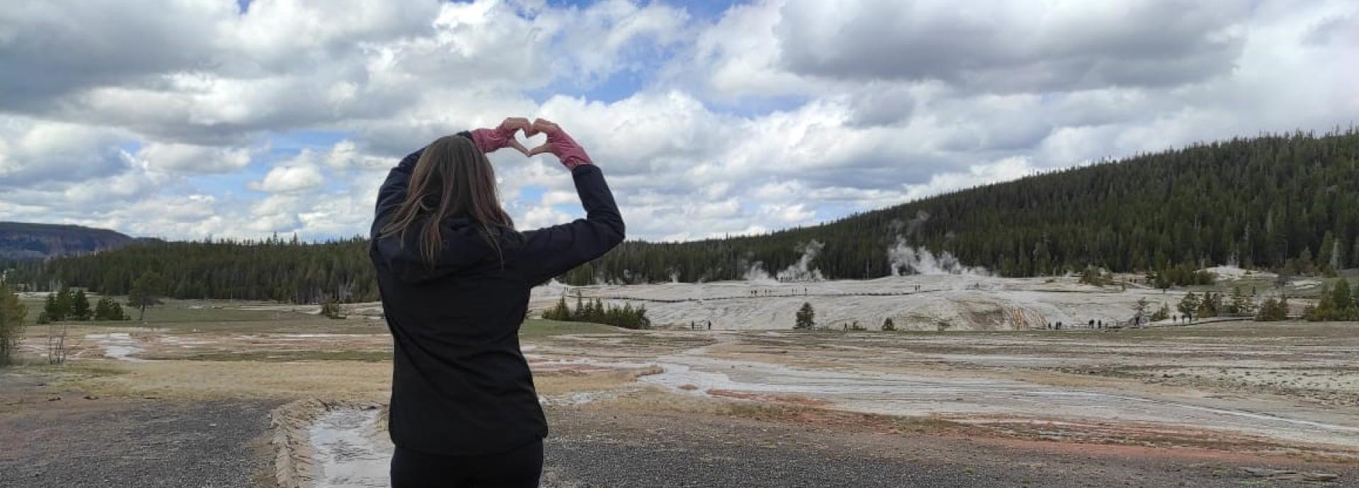 Maria standing in with her back to camera, forming a heart with both of her hands.