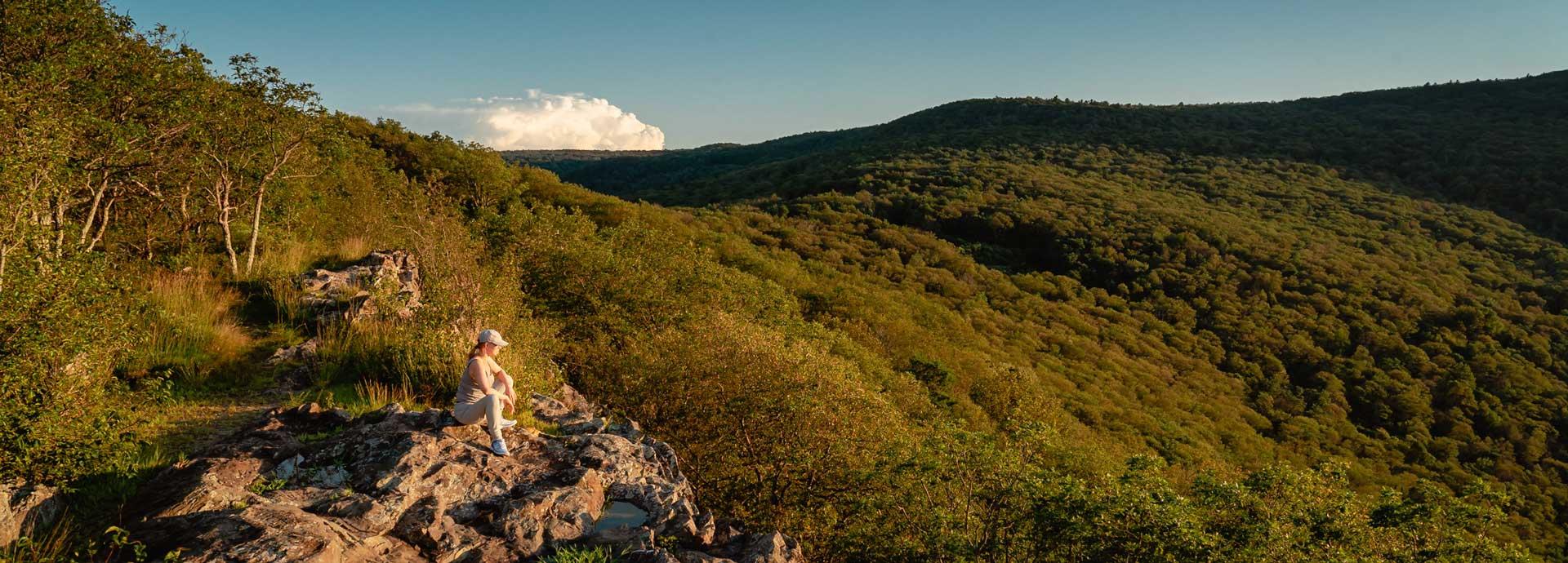 Carita Eklund sitting on a rock in a mountaneous landscape. Photo taken by Jan Gustafsson