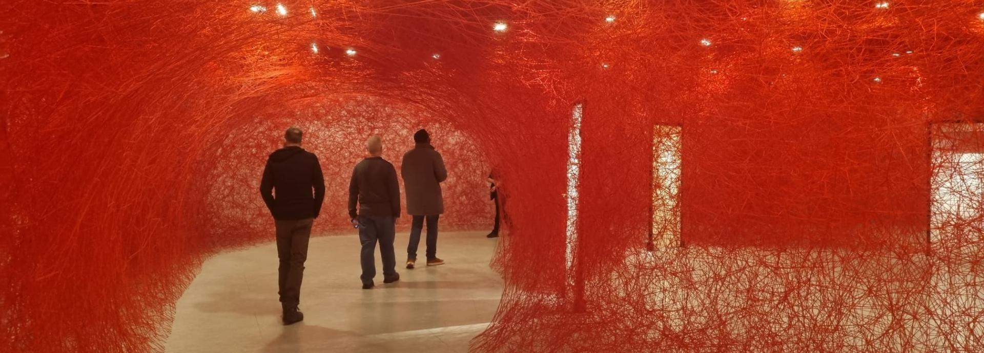 People walking in a red art installation at EMMA museum