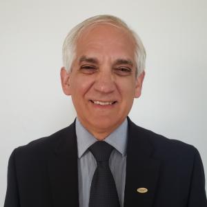 Senior Adviser Edward Roslof smiling at the camera. He's wearing a suit and a Fulbright pin.