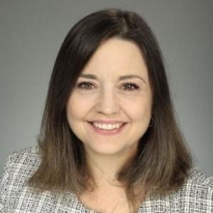 Photo of a woman with shoulder-length hair with a grey jacket