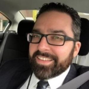 Photo of a man smiling, sitting in a car