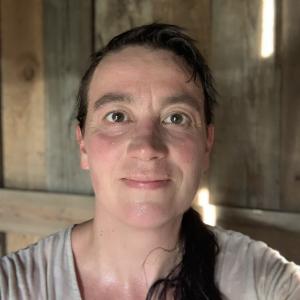 Head-shot of a brown haired person in the sauna with a grey shirt on