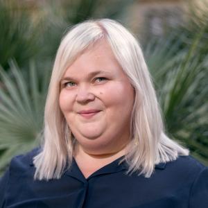 A person with blonde hair and dark blue shirt