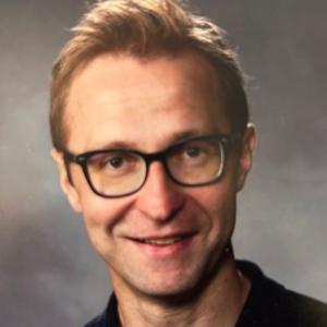 Photo of short-haired man with black glasses smiling