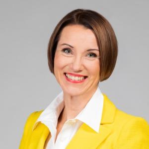 Woman with short hair smiling in a yellow jacket